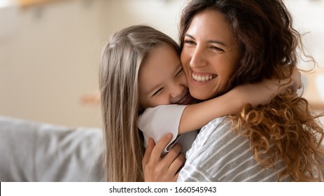 Cute little girl hug cuddle excited young mum show love and affection, smiling mother and funny small preschooler daughter have fun at home embrace sharing close tender moment together - Shutterstock ID 1660545943