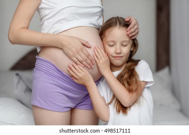 Cute little girl hugging belly of her pregnant mother, listening - Shutterstock ID 498517111