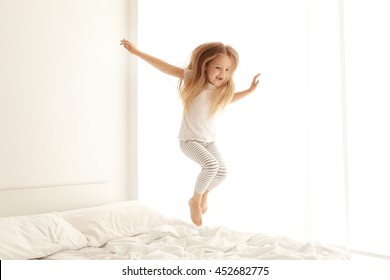 Cute Little Girl Jumping On White Bed