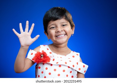 Cute Little Girl Kid Saying Hi And How Are You By Looking At Camera On Blue Color Background - Concept Of Child Greeting