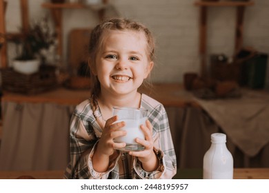 Cute little girl in the kitchen drinking yogurt and eating a bun. High quality photo - Powered by Shutterstock