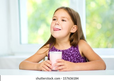 Cute Little Girl Is Licking Her Lips While Drinking Milk