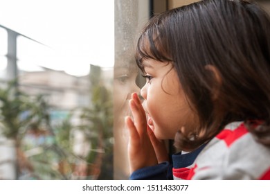 Cute Little Girl Looking Out Through A Window With Her Hands And Face Pressed Up Against A The Glass