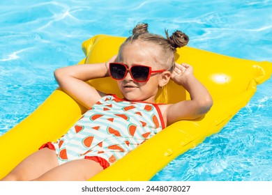 Cute little girl lying on inflatable mattress in swimming pool with blue water on warm day on tropical vacations. Summertime activities concept. advertising of tour operators and all-inclusive hotels - Powered by Shutterstock