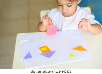 Cute little girl make applique  glues colorful house, applying color paper using glue while doing arts and crafts in preschool or home. Idea for children's creativity, an art project made of paper.