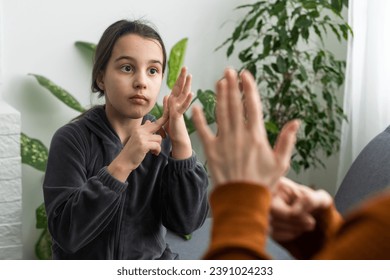 Cute little girl make hand gesture learning sign language with mom or female nanny, smiling small kid practice nonverbal talk with teacher at home, preschooler disabled child have lesson with tutor - Powered by Shutterstock