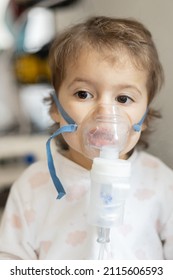 Cute little girl in the mask of an inhaler. Procedure of inhalation at home. Kid taking respiratory therapy with nebulizer.  - Shutterstock ID 2115606593