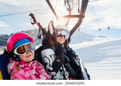 Cute little girl with mom in helmet and goggles having fun sitting on ski lift chair enjoying winter ski vacations in alpine austrian mountains. Happy family portrait winter sport holidays - Powered by Shutterstock