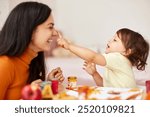 Cute little girl and mom spending good time painting autumn yellow leaves together