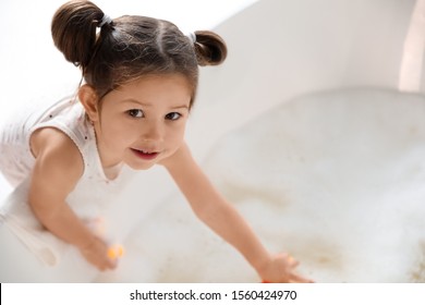 Cute little girl near tub in bathroom. Space for text