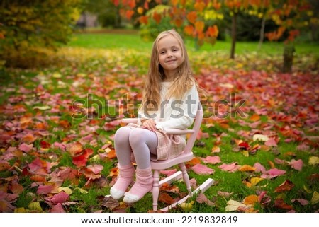 Cute little girl on a swing chair in an autumn garden