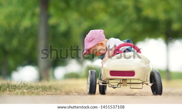 cute\
little girl in pedal car in park on summer\
day