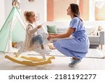 Cute little girl with pillow, rocking horse and her mother at home