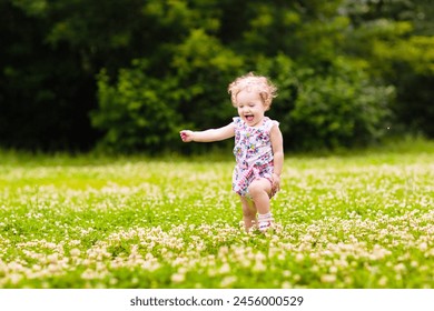 Cute little girl in pink dress playing in blooming spring park with first white wild anemone flowers. Child on Easter egg hunt in blooming garden. Kids play outdoor picking flower bouquet. - Powered by Shutterstock