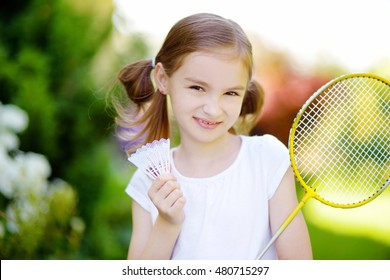 Cute little girl playing badminton outdoors on warm and sunny summer day