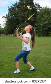 Cute little girl playing badminton on green grass outdoor.