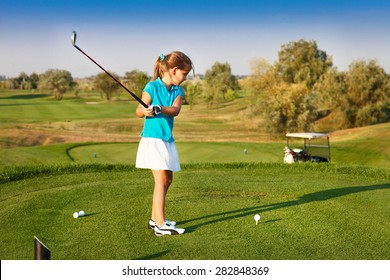 Cute little girl playing golf on a field outdoor. Summertime