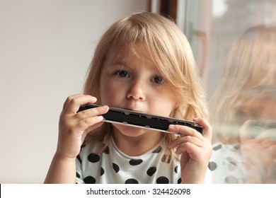 Cute little girl playing harmonica, music concept
