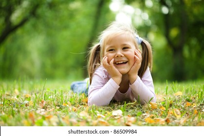 Cute kleine Mädchen spielt mit Blättern im Herbstpark