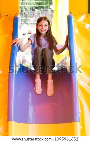 Cute little girl is playing on the playground.
The child moves out with slide on the court.
