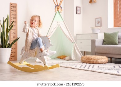 Cute Little Girl Playing With Rocking Horse At Home