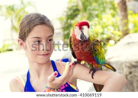Cute little girl playing with a Scarlet Macaw Parrot while on cruise vacation in Mexico.