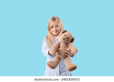 Cute little girl with plush teddy bear on blue background
