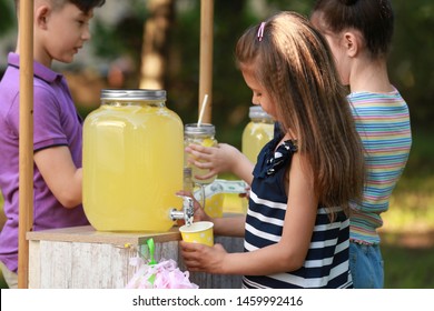 Cute little girl pouring natural lemonade into cup in park. Summer refreshing drink - Powered by Shutterstock