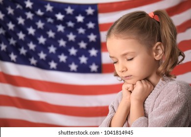 Cute little girl praying for America and flag on background - Powered by Shutterstock