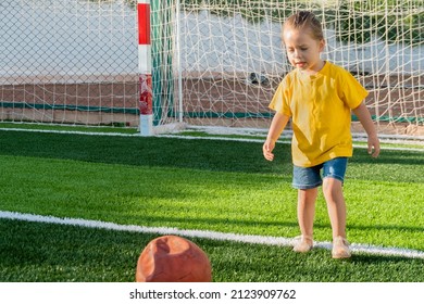 Cute little girl preparing kick soccer ball on green sports field at sunset time. Kid playing football with her family  - Powered by Shutterstock