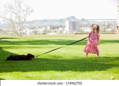 Cute little girl pulling her dog from its leash, trying to bring it with her