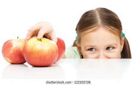 Cute little girl is reaching apple on table, isolated over white