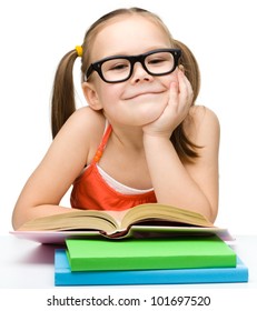 Cute Little Girl Is Reading Book Wearing Glasses, Isolated Over White