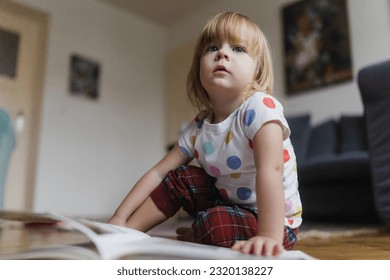 Cute little girl reading book sitting on the floor. - Powered by Shutterstock