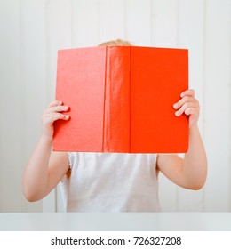 Cute Little Girl Reading Book, Covering Her Face.