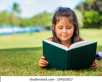 Cute Little Girl Reading Outside On Grass