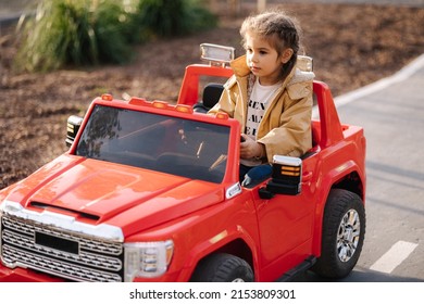Cute little girl rides in a mini city on a red electric car jeep. Adorable little girl road in toy city. Plays for entertaiment