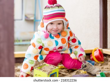 Cute Little Girl In A Sandbox  In Cold Weather