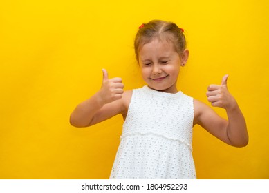 Cute little girl shows class with her hands. Beautiful girl with closed eyes in a white dress on a yellow background. The concept of discounts. Sale. Copy space - Shutterstock ID 1804952293
