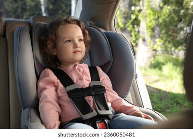 Cute little girl sitting in child safety seat inside car - Powered by Shutterstock