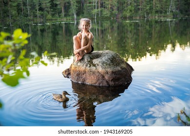 Cute Little Girl Sitting On A Rock In Lake. Enjoying Summer Vacation. Child And Nature. Happy Isolation Concept. Exploring Finland. Scandinavian Landscape. 