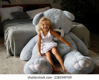 Cute Little Girl Sitting On Her Toy Big Bear At Home, Happy Childhood Concept, Indoor Horizontal Portrait