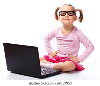 Cute Little Girl Is Sitting On Floor With Her Laptop, Wearing Glasses, Isolated Over White