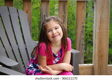 Cute little girl sitting outside with greenery as background - Powered by Shutterstock