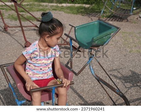 Cute little girl sitting in swinging.Wearing indian pink dress.Black eyeglass with different pose portrait photo.Using for ai editing and wallpaper also.