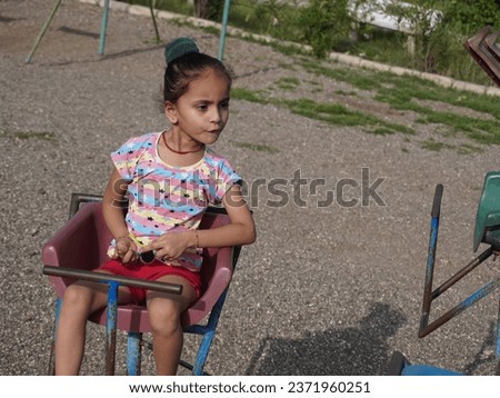 Cute little girl sitting in swinging.Wearing indian pink dress.Black eyeglass with different pose portrait photo.Using for ai editing and wallpaper also.