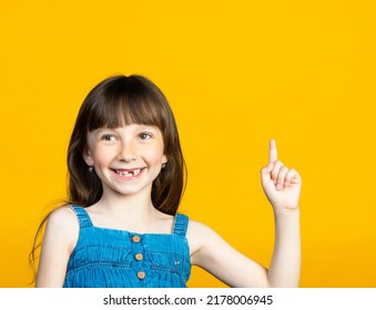 A cute little girl smiles a toothless smile with her front tooth falling out, and with her finger up. The tooth fairy will bring a new tooth. High quality photo - Shutterstock ID 2178006945