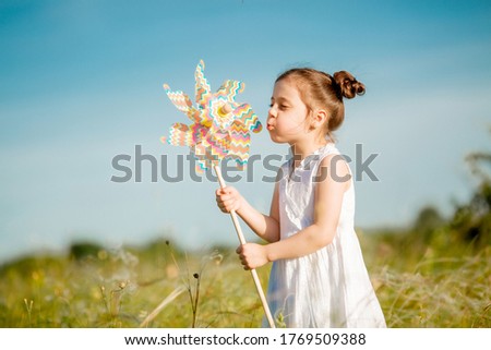 Cute little girl smiling summer in the field holding a windmill