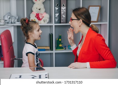 Kleines Mädchen im Büro des Sprachtherapeuten. Kleines Kind, das zu Hause mit Therapeuten in einer Privatstunde Artikulation praktiziert.