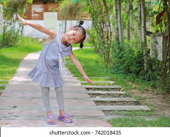 Cute little girl stand and stretch arms in the tree tunnel at resort on the morning.